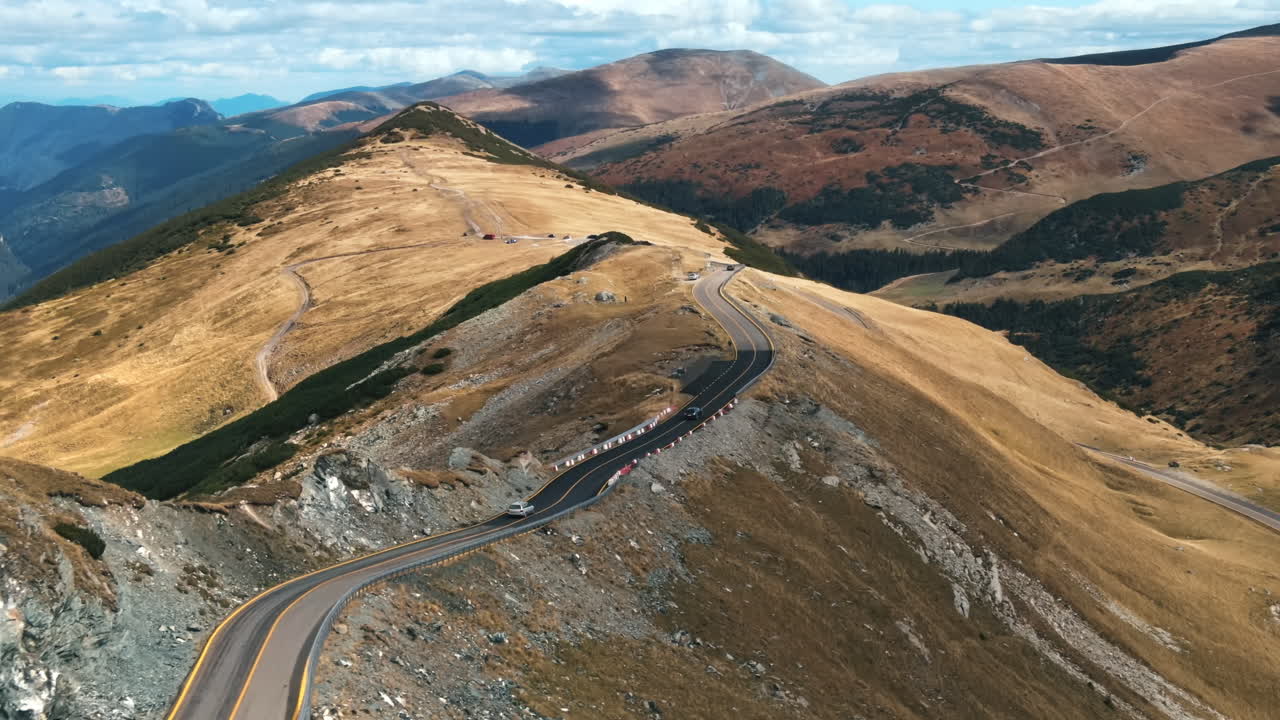 Aerial drone view of nature in Romania. Carpathian mountains, sparse vegetation, Transalpina road with cars
