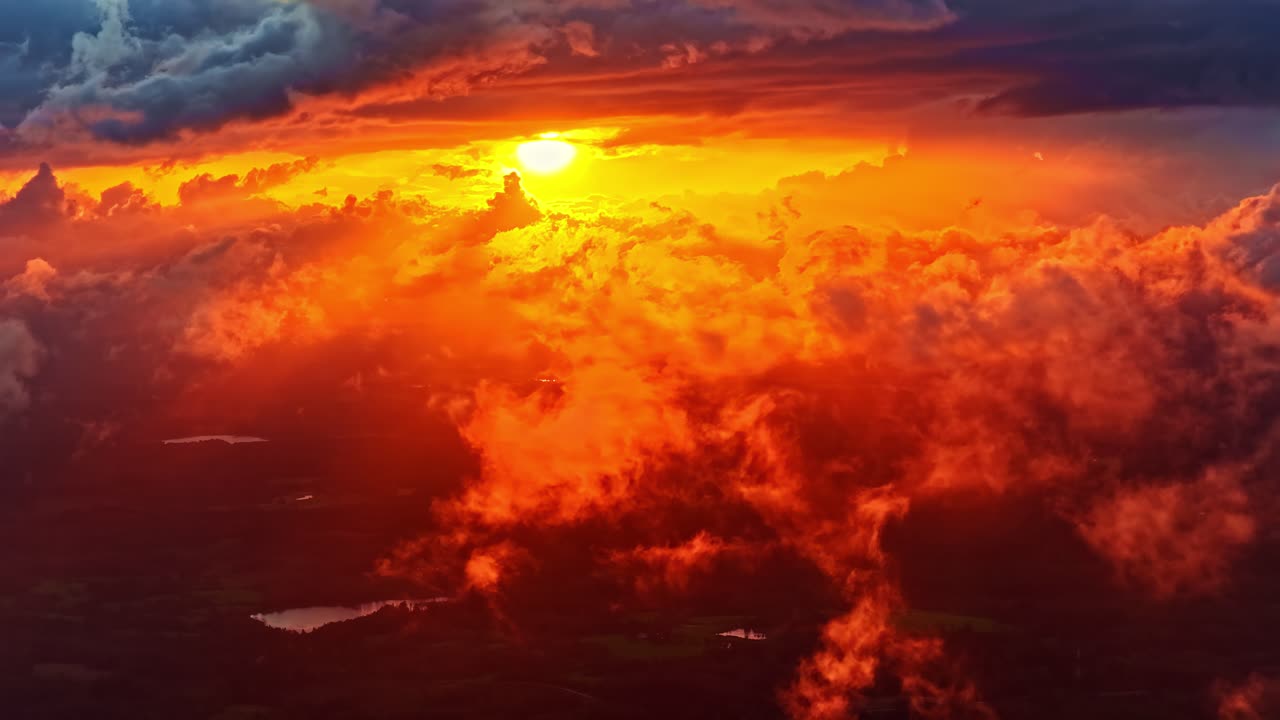 Feurig rotes, oranges Sonnenlicht ergießt sich während des Sonnenuntergangs durch dramatische Wolken und erhellt den Himmel mit intensiver Farbe und Tiefe über der Landschaft