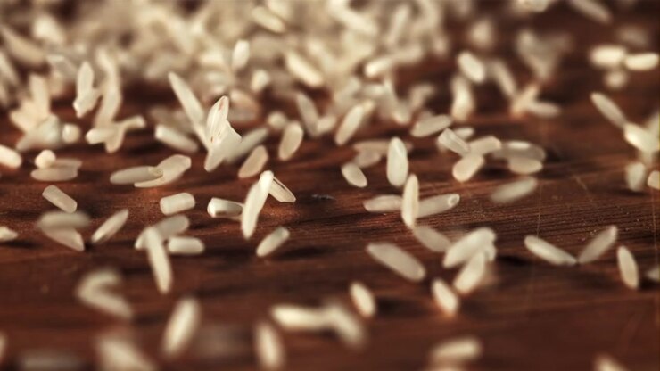 Raw White Rice Grains Falling onto a Dark Wooden Surface