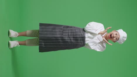 full body of asian woman chef smiling and saying wow while standing in the green screen background studio