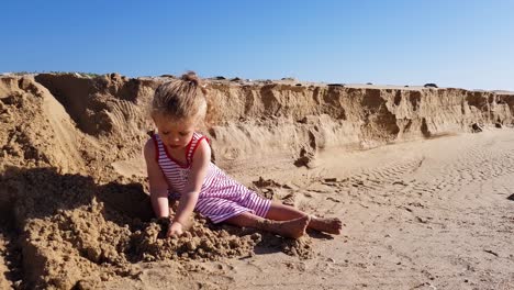 toddler girl is playing with sea sand on the beach and having fun