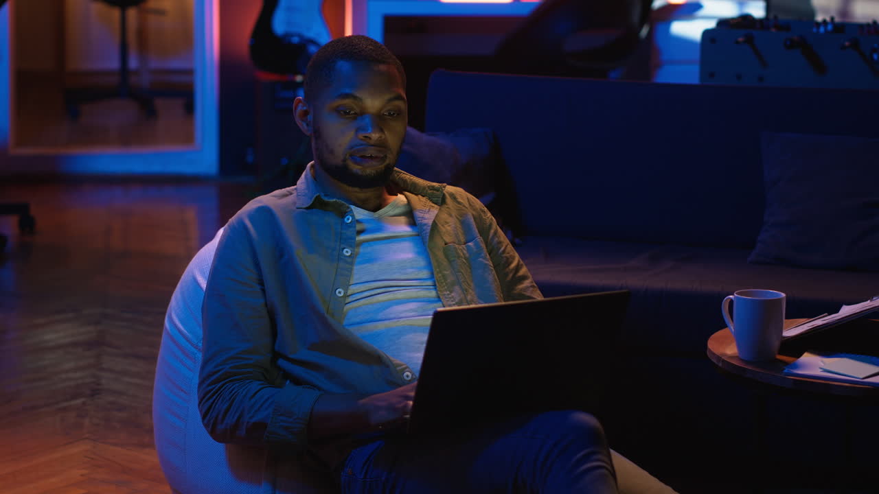 Vertical Video Black guy does remote work from his living room with the laptop