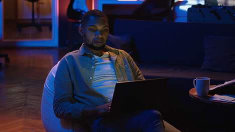 vertical video black guy does remote work from his living room with the laptop