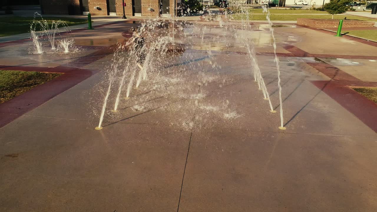 Young Boy Splashing Playing Through Water Tunnel at a Splash Pad