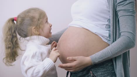 Kleines-Mädchen-Hat-Spaß-Mit-Junger-Schwangerer-Mama-Im-Beleuchteten-Raum