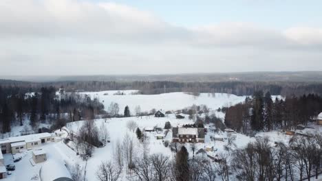 Volando-Sobre-Un-Pequeño-Pueblo-Llamado-Ligatne-Hacia-La-Bandera-Letona-En-Una-Lejana-Distancia-En-Un-Día-De-Invierno-Nevado