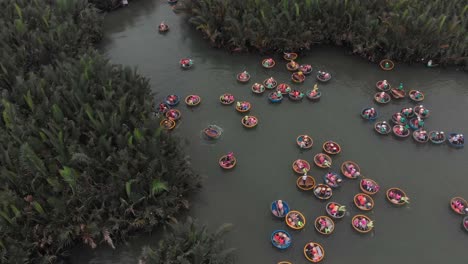 Tourists-having-an-excursion-and-fun-in-Thu-Bon-river-coconut-boats-Vietnam,-aerial