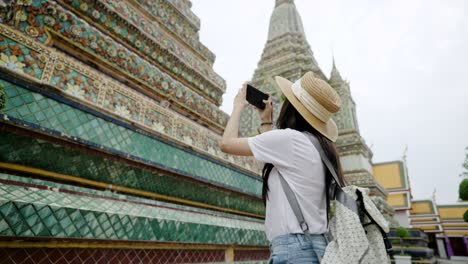 cheerful young asian woman traveling at wat pho temple in bangkok, thailand.