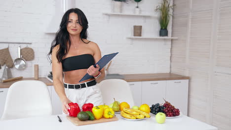 healthy food at home. happy brunette woman is making notes in modern kitchen. vegan and vegetarian lifestyle. food for slimming concept