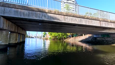 boat travels under bridge on sunny day