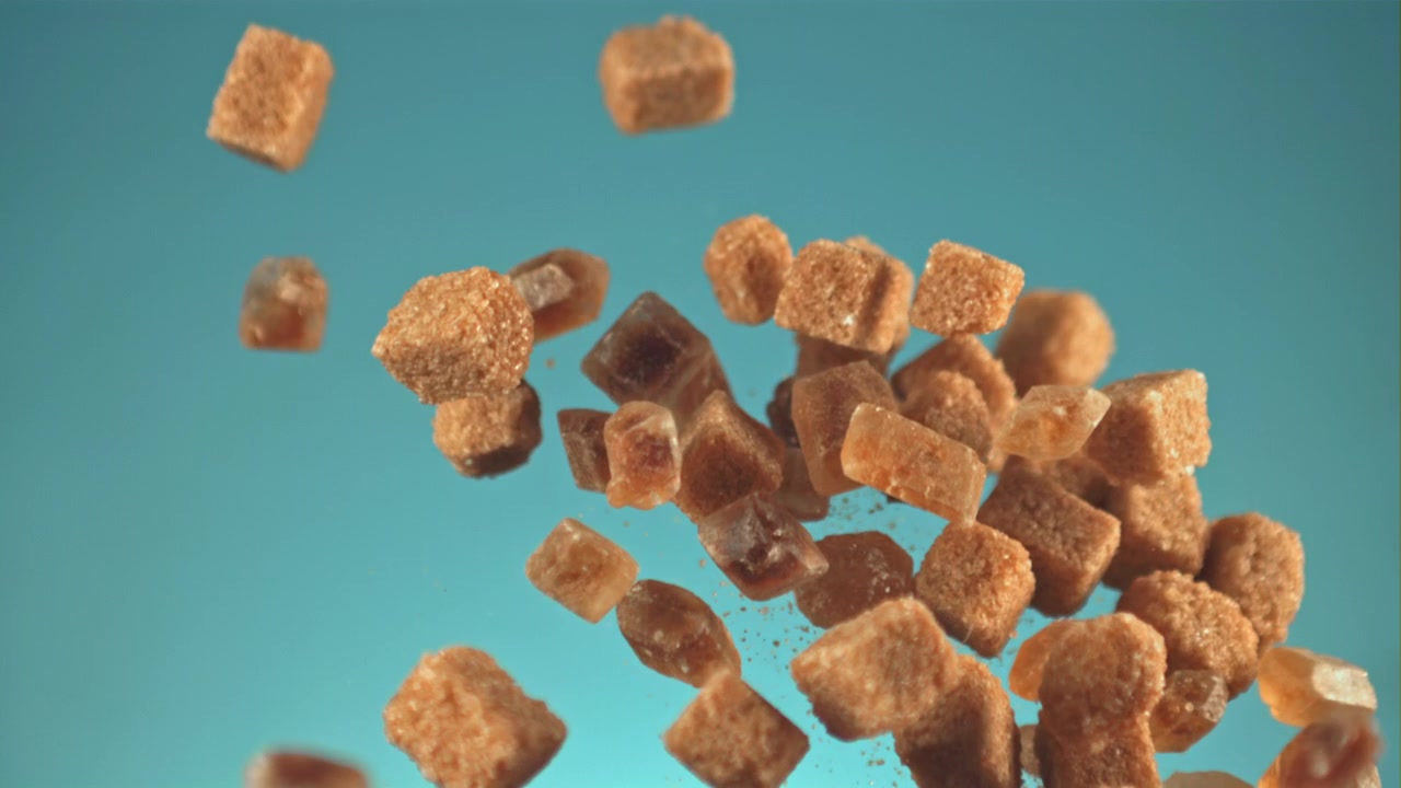 Brown Sugar Cubes Falling in Slow Motion Against a Blue Background