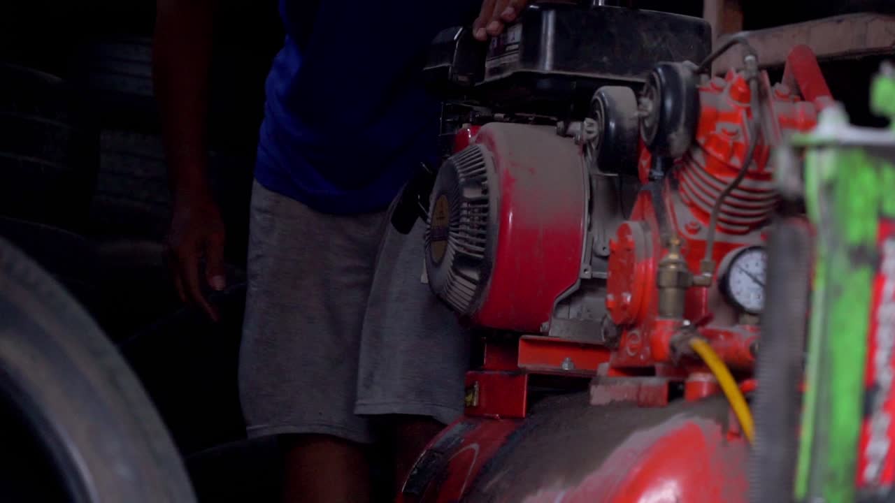 Slow motion - A man starting air compressor belt driven machine on workshop