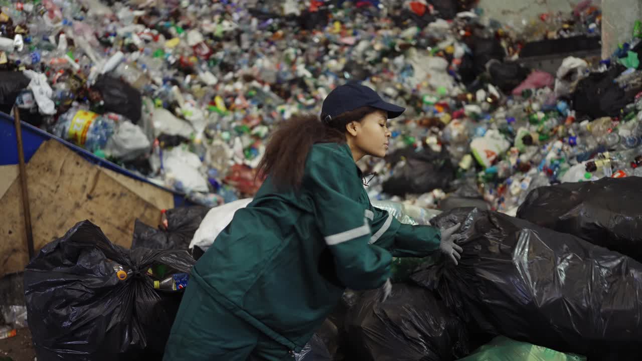 mujer afroamericana clasificando bolsas de basura en una planta de reciclaje. control de la contaminación