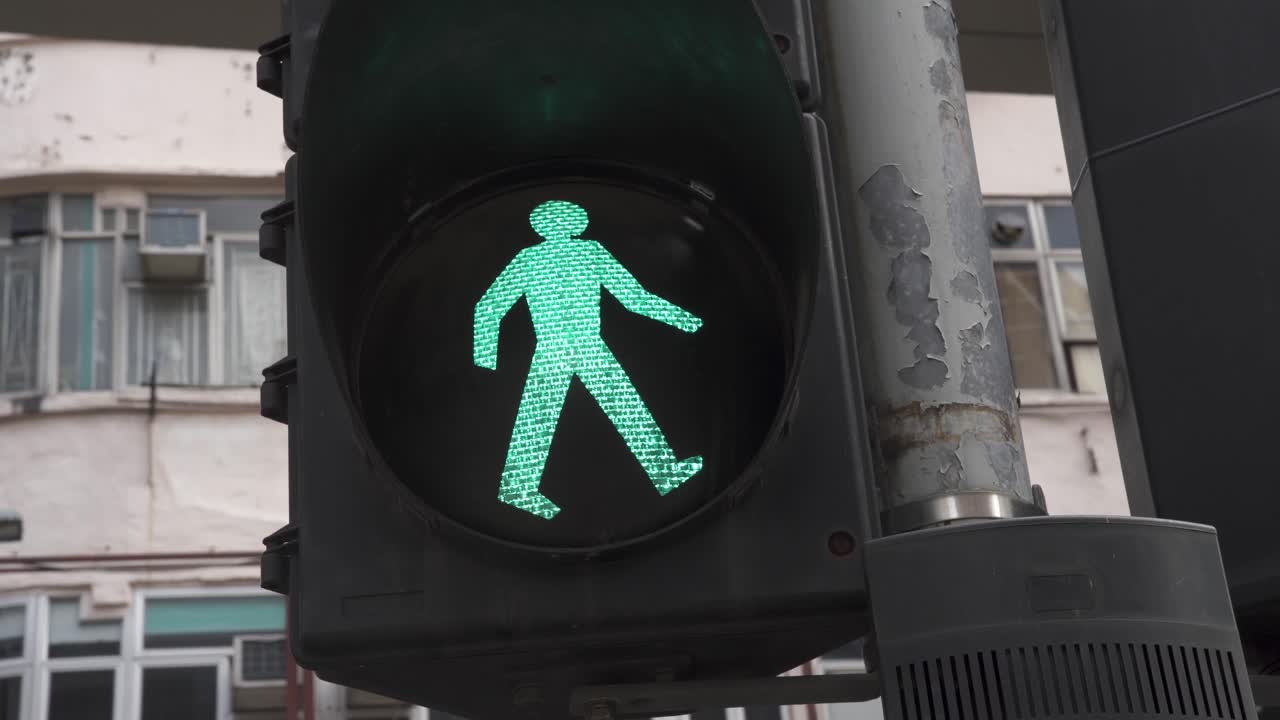 A pedestrian traffic light has the green light on for people to walk through a crossing zebra in Hong Kong.