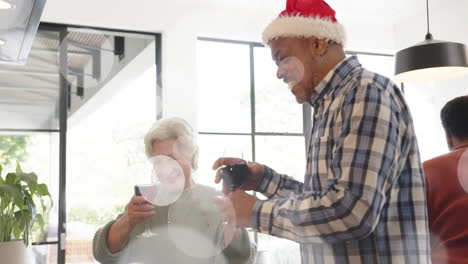 Animación-De-Puntos-De-Luz-Sobre-Diversos-Amigos-Mayores-Tomando-Vino-En-Navidad-En-Casa