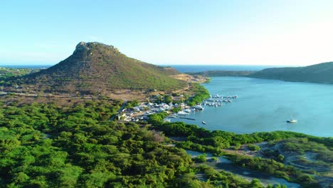 drone parallax orbit around fishing boat dock pier harbor at base of cinder cone on caribbean island