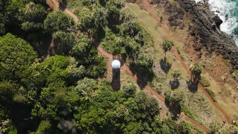 vista giratoria única de un faro de estilo colonial encaramado en un promontorio escénico con olas estrelladas