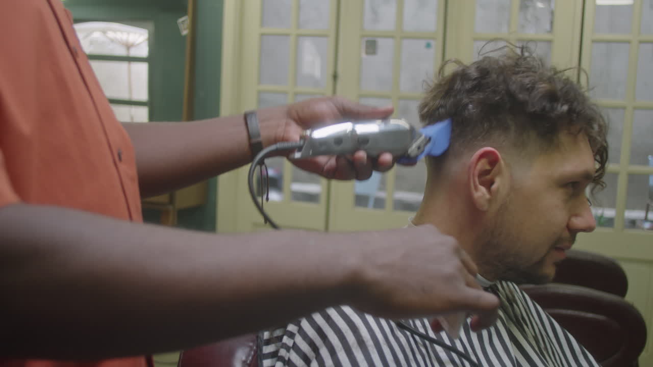 Barber Doing Haircut for Client with Trimmer and Comb