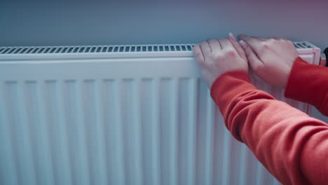 manos encendiendo la temporada de calefacción de cerca, la mujer haciendo la temperatura de la batería más tratando de mantenerse caliente en invierno