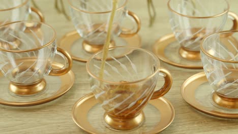 pouring of tea into a transparent, color-infused glass