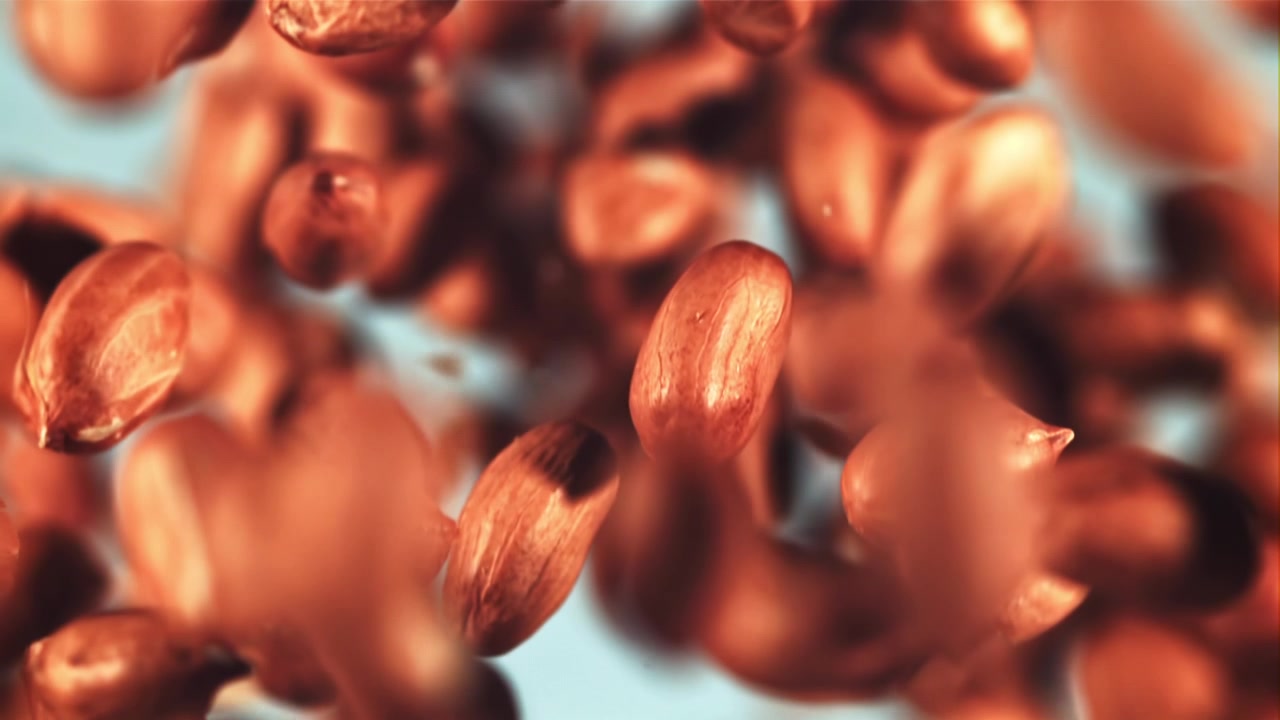 Shelled Peanuts Falling in Super Slow Motion on Blue Background
