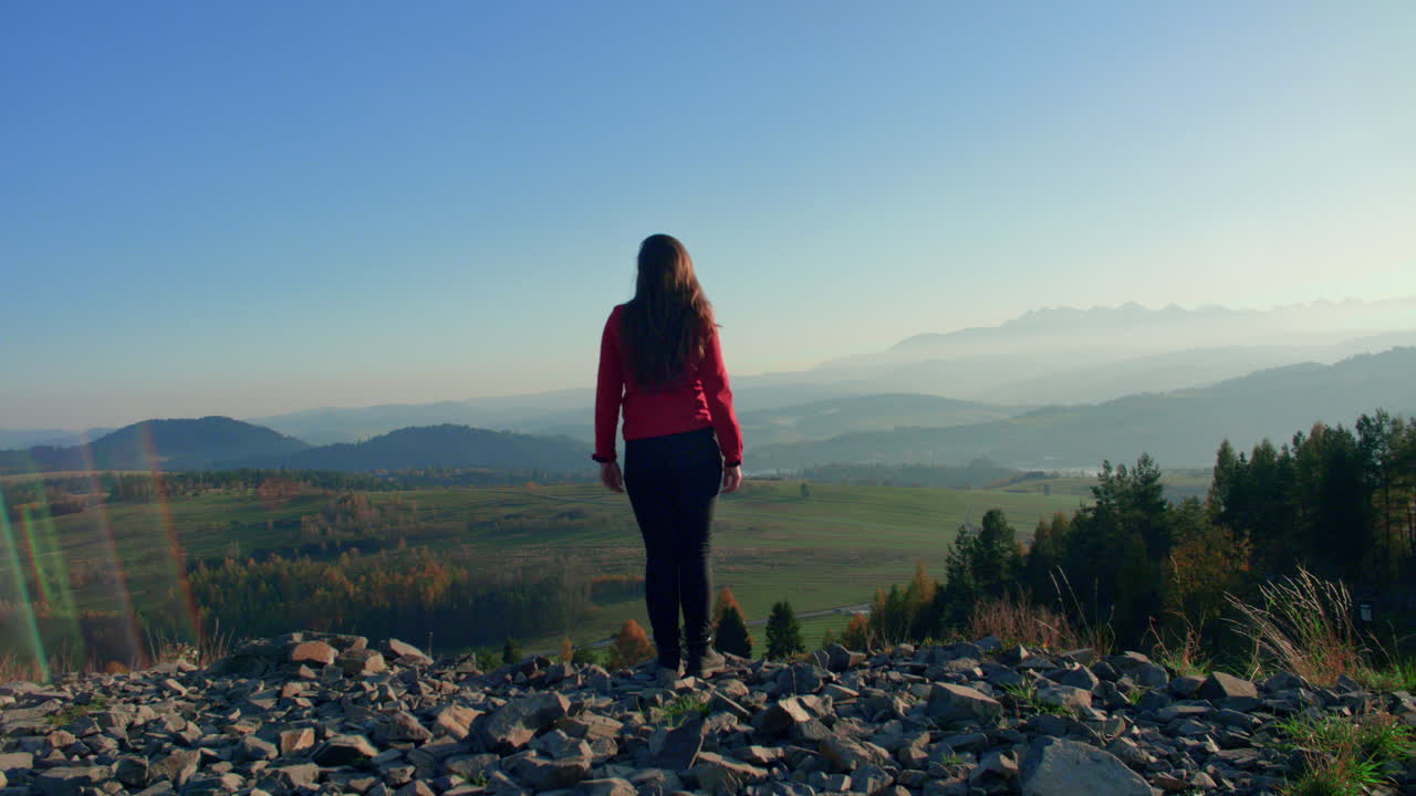chica caminando hacia el acantilado en la cima de la colina mirando el paisaje lleno de colinas y montañas
