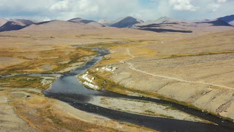 Luftdrohne,-Die-An-Einem-Sonnigen-Tag-Hoch-über-Einem-Natürlichen-Fluss-Und-Weißen-Campingzelten-In-Der-Hochgelegenen-Alpenebene-Des-Deosai-Nationalparks-Zwischen-Skardu-Und-Astore-Tal-In-Pakistan-Fliegt