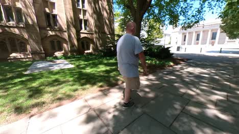 4k pan following man walking on campus