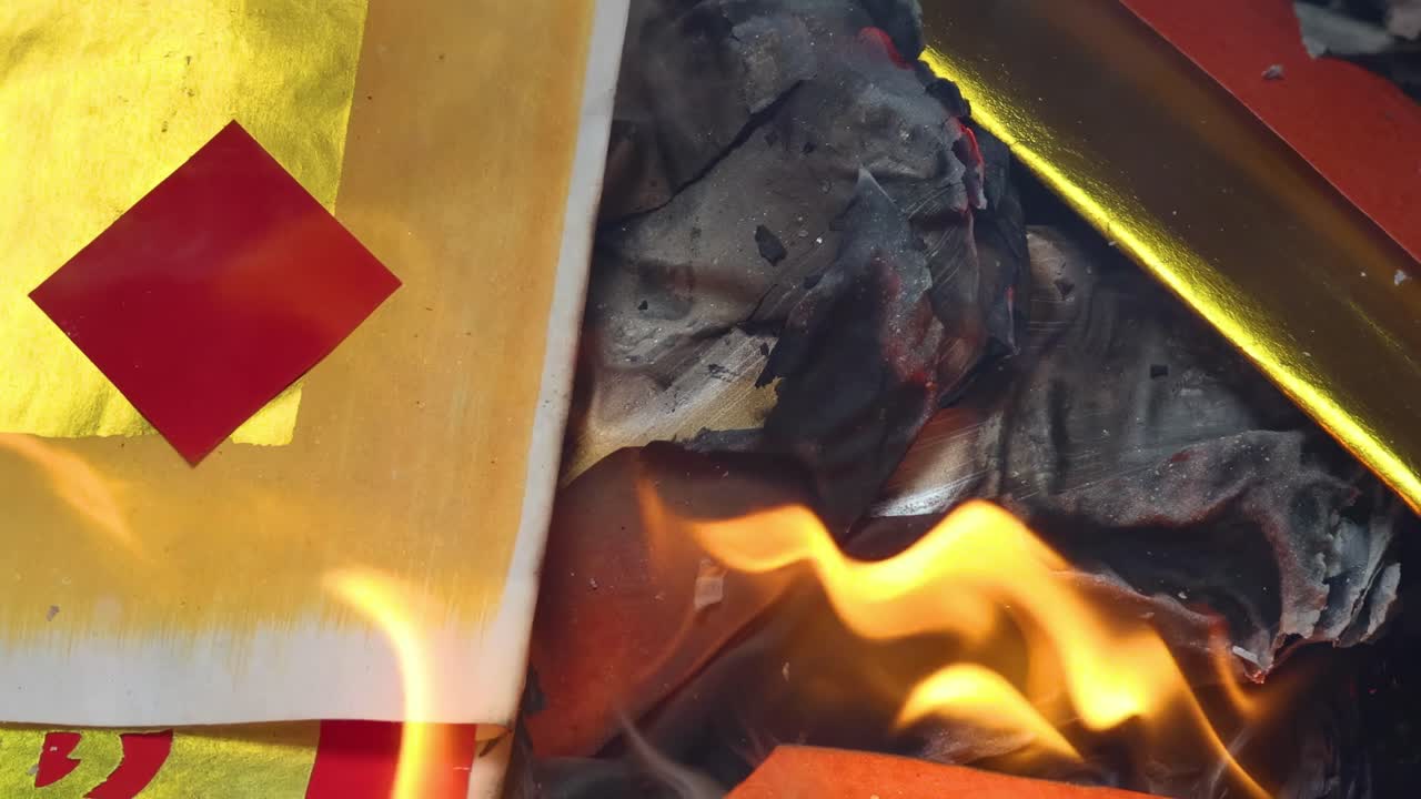 Detailed view of flames consuming joss paper with red diamond pattern.