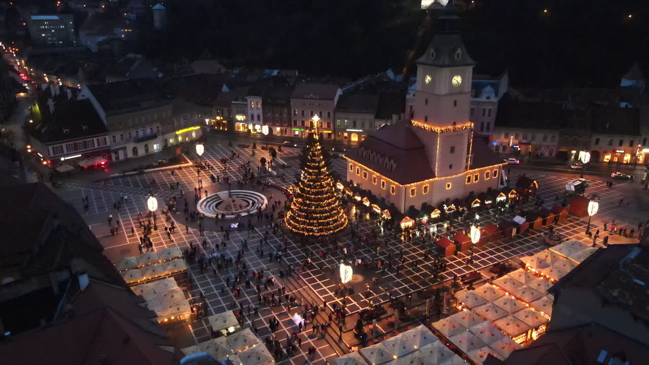 Aerial drone view of The Council Square at dusk in Brasov, Romania. Old city centre decorated for Christmas. County Museum of History, buildings, people