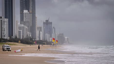 life saver removing flags on the beach during heavy storms over beaches on the gold coast causing rough seas and rain, gold coast, australia.