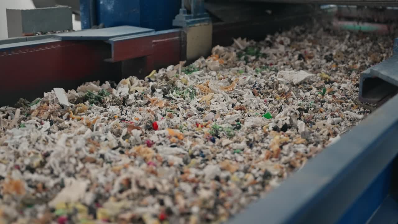 공장 재활용 공정을 통해 컨베이어를 따라 이동하는 잘게 분쇄된 고무 폐기물