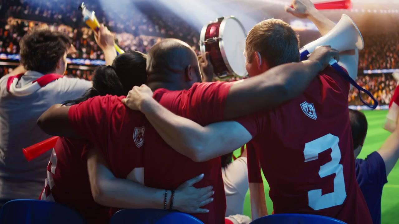 Amigos eufóricos celebran la victoria del partido en las gradas del estadio de fútbol.