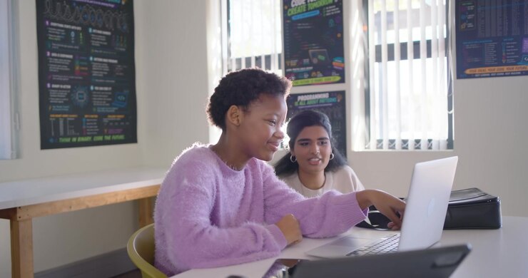Diverse teens working at code lab, camera shifting causing right pair moving closer, typing laptop