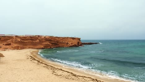 empty rocky cape with sandy beach near wavy sea