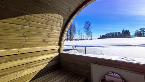 outdoor wooden barrel sauna looking outside at winter snow timelapse