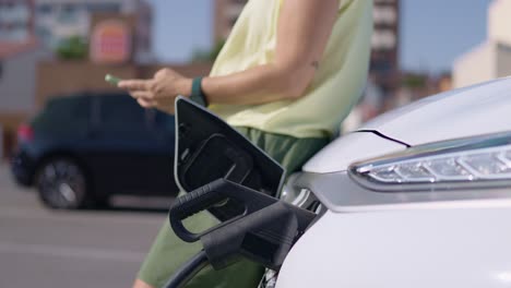 electric car charging with person using smartphone