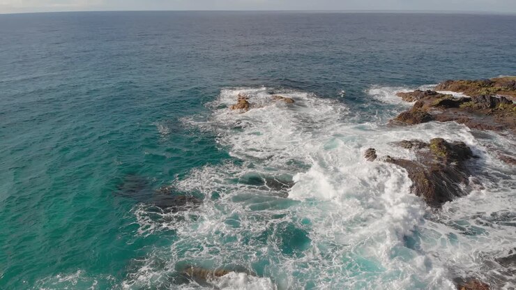Rapido arretramento e inclinazione dalla costa rocciosa rivela le scogliere della montagna di roccia a picco sulle acque turchesi dell'oceano