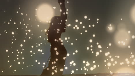 golden glowing spots moving against woman performing yoga background