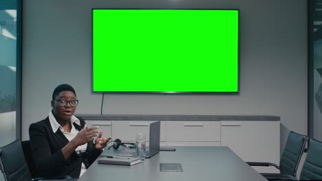 young black businesswoman making presentation in conference room with chroma key tv