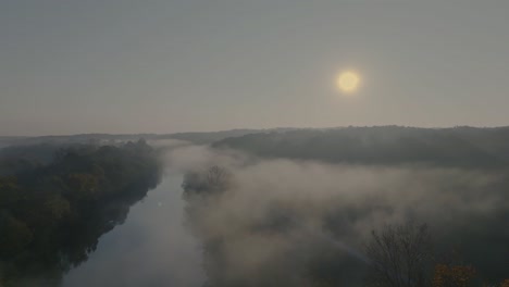 Hochauflösende-Drohnenaufnahmen:-Fluss-Am-Frühen-Morgen-Mit-Aufsteigendem-Nebel,-Eingerahmt-Von-Herbstlich-Gefärbten-Bäumen