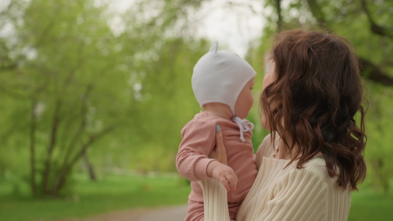 Concerned Mother Holds Child Protectively, Mother Cradles Baby With Watchful Care And Kindness, Caring Mother Gently Holds Her Baby Close While Attentively Observing Surroundings In Park Setting