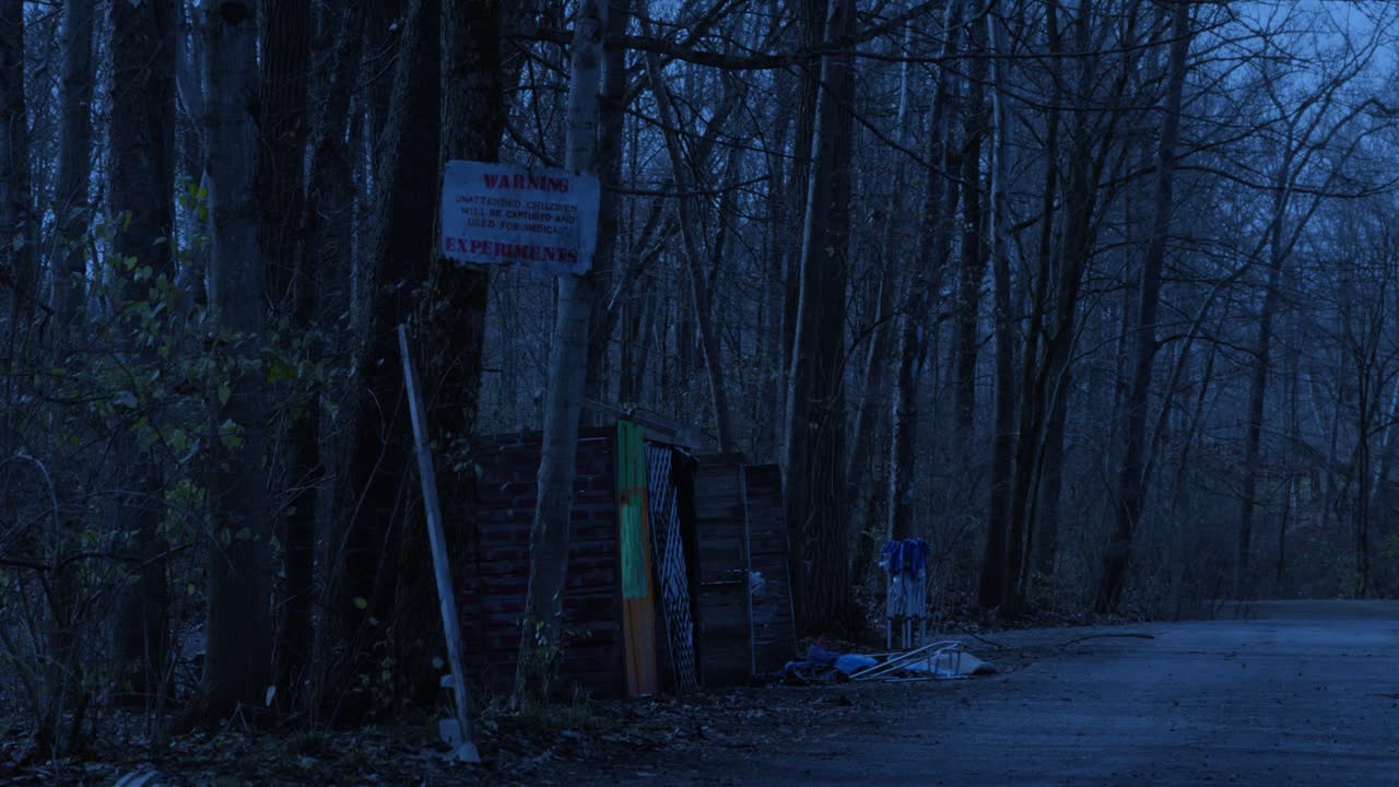 Broken down abandoned shack warning against trespassing in ominous bare leafless woodland