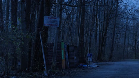 Broken-down-abandoned-shack-warning-against-trespassing-in-ominous-bare-leafless-woodland