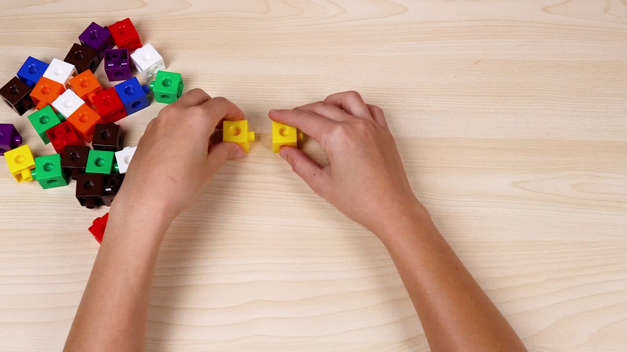 manos arreglando cubos de colores en una mesa