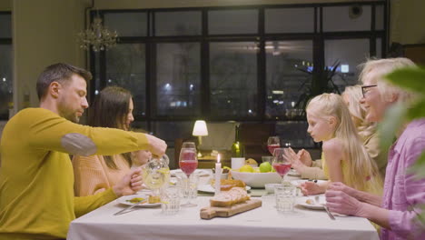 Side-View-Of-A-Family-Having-Dinner-Sitting-At-A-Table-And-Enjoying-A-Great-Time