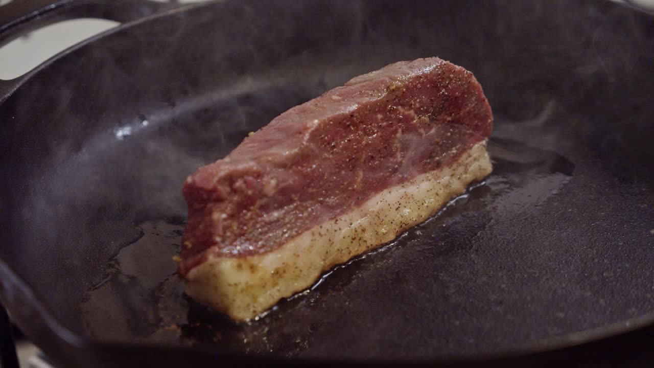 bistec de carne a la parrilla en una sartén caliente y liberando su aceite