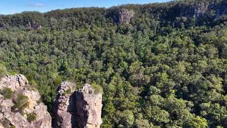 drone footage captures nimbin rocks surrounded by dense forest under bright daylight, showcasing natural beauty and geological formations