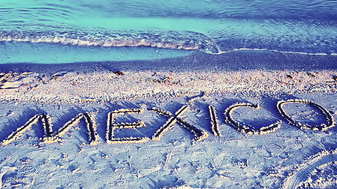 Trooppinen ranta ja hiekkaan kirjoitettu "Mexico"-teksti. Hiekkakirjoitus rannalla.