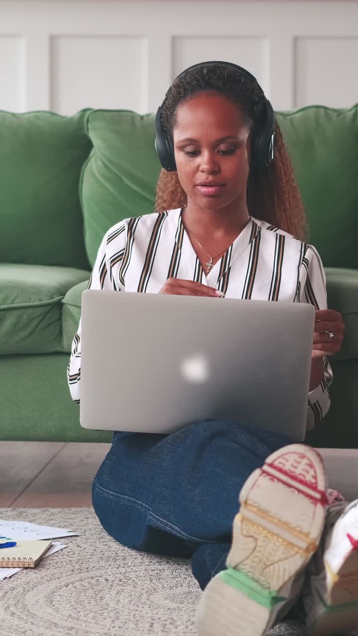 Young african american woman uses laptop to record video interview sits on floor